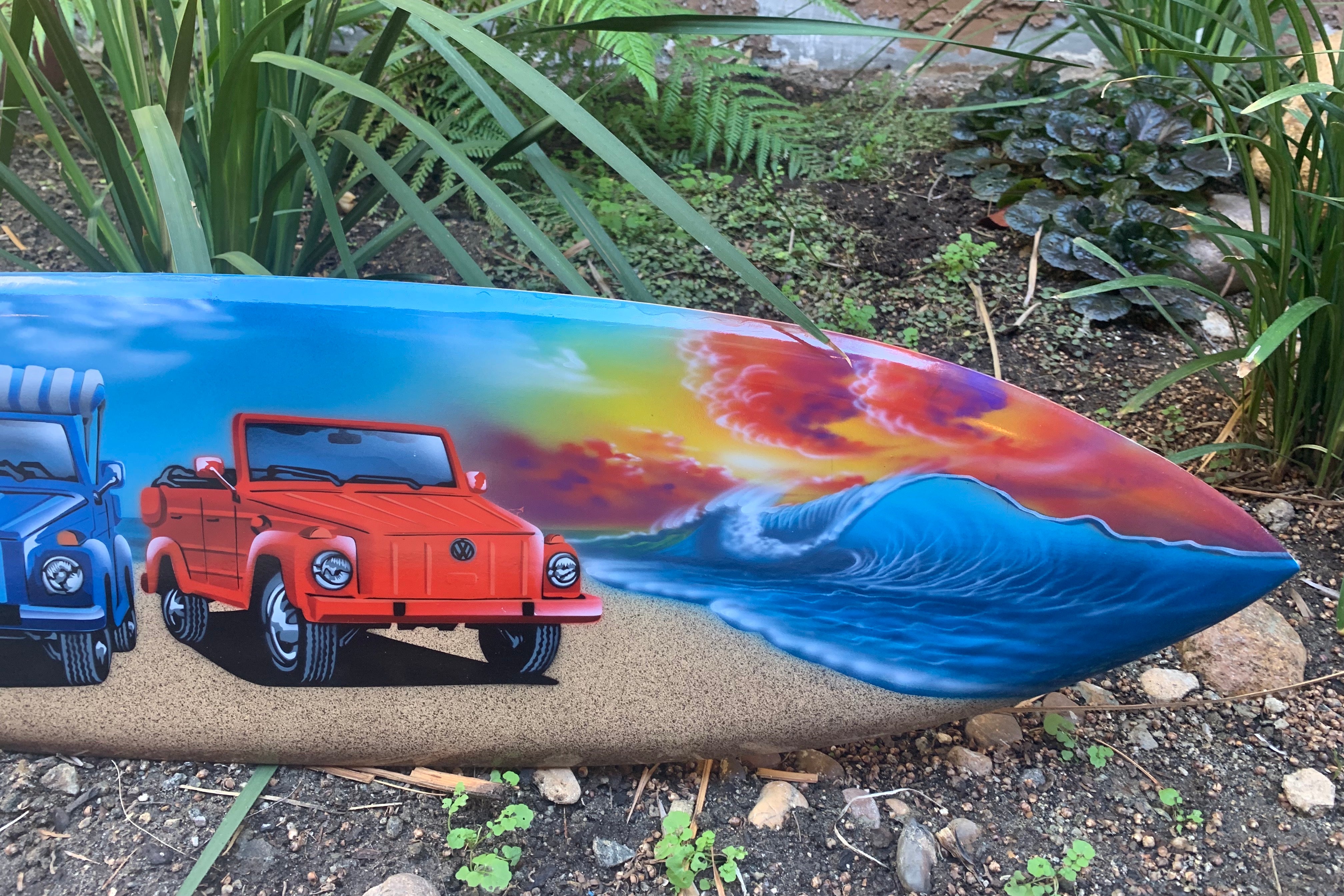 colorful surfboard painting with red vintage jeep and blue car beside ocean wave