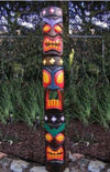 Tall colorful tiki totem pole with multiple faces in a garden setting