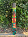 Colorful tiki totem pole painted with a palm tree design in a garden
