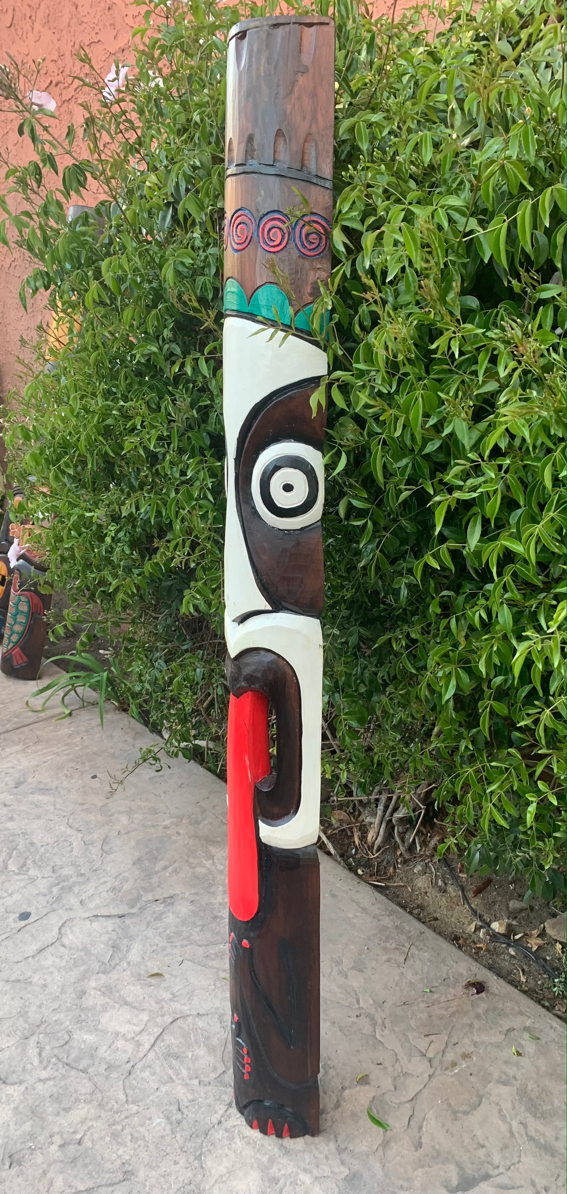 Colorful totem pole sculpture with spirals and bold facial design outdoors