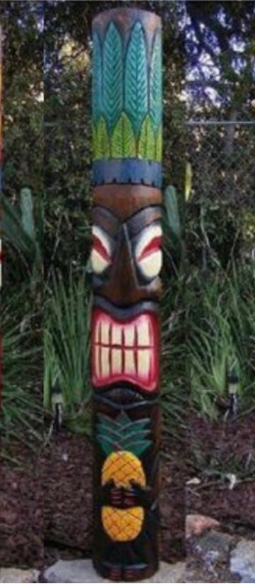 Colorful carved totem pole with leaf-patterned designs in a garden