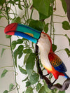 Colorful toucan sculpture perched among green leaves and vines