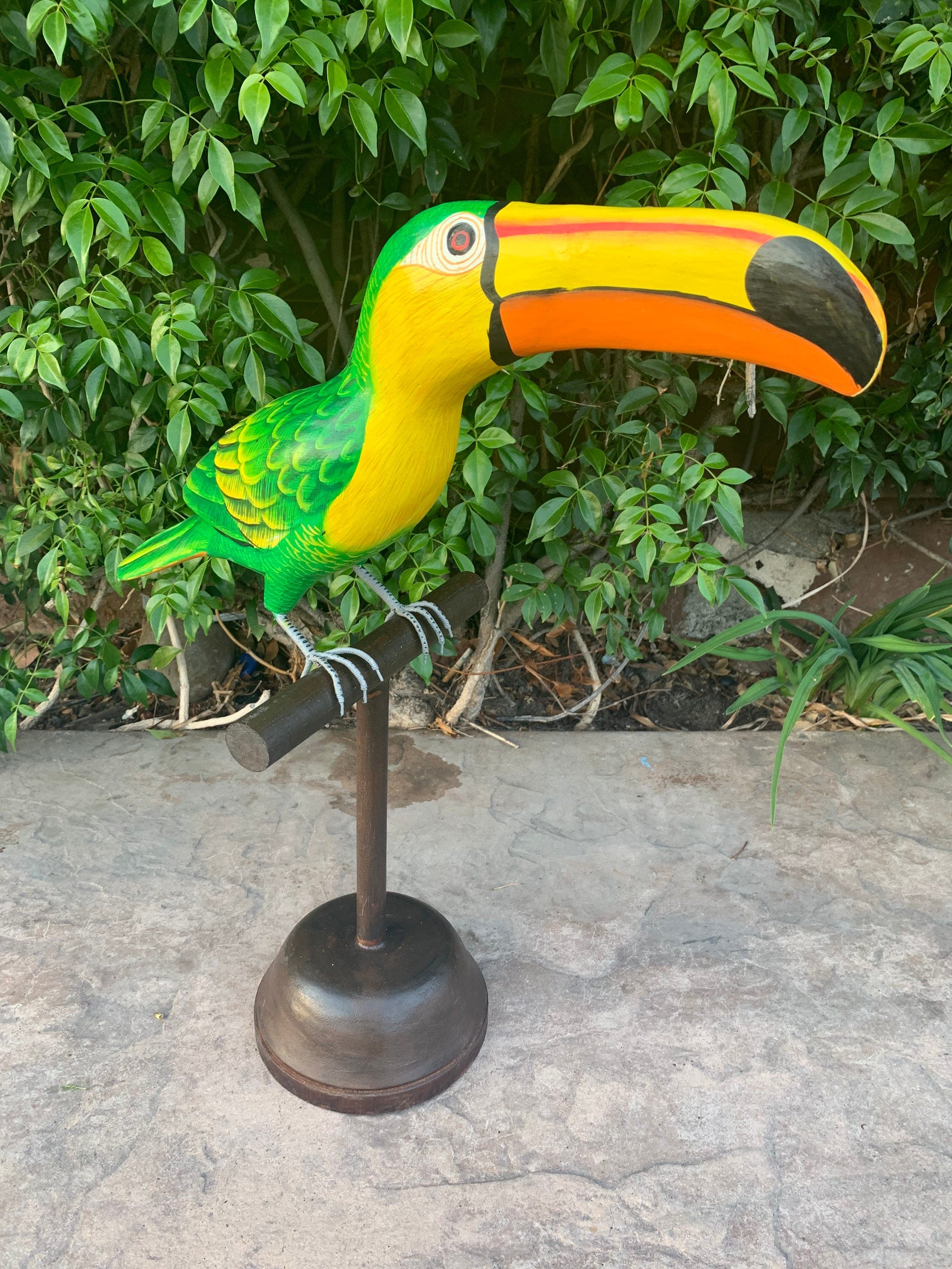 Colorful toucan sculpture perched on a metal stand with green foliage background