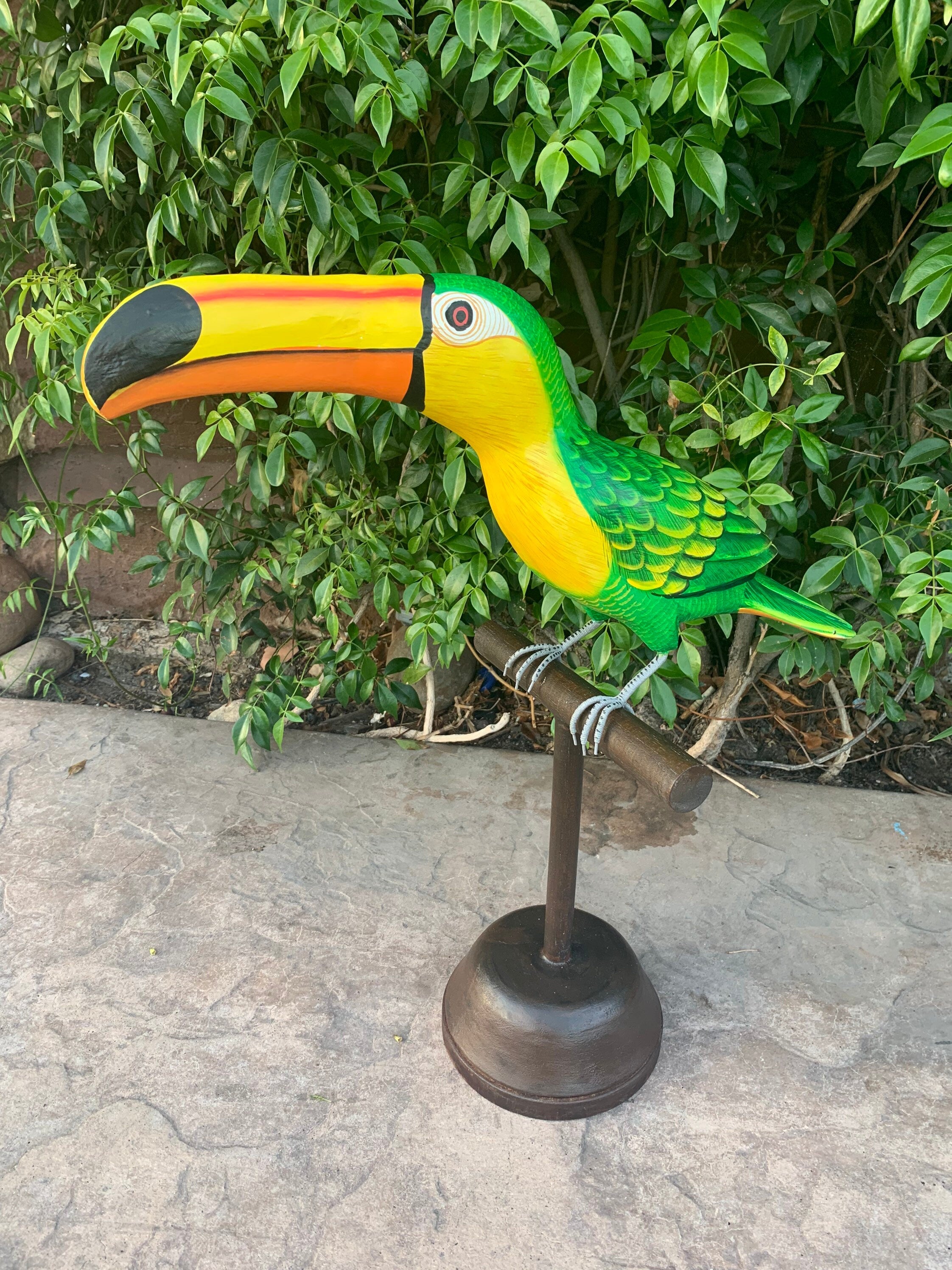 Colorful toucan sculpture perched on a stand in a garden