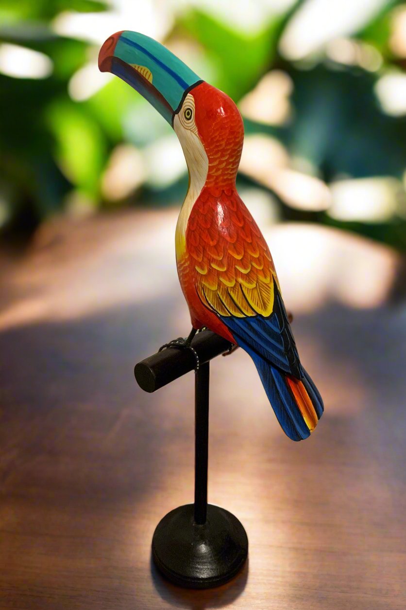 Colorful wooden toucan sculpture perched on a black stand