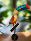 Colorful toucan wooden sculpture with bright rainbow beak perched on a stand