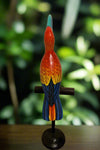 Colorful carved wooden parrot sculpture perched on a stand.