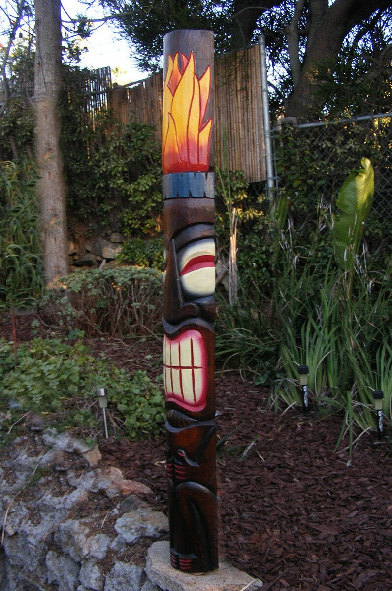 Colorful wooden totem pole sculpture in a garden setting.