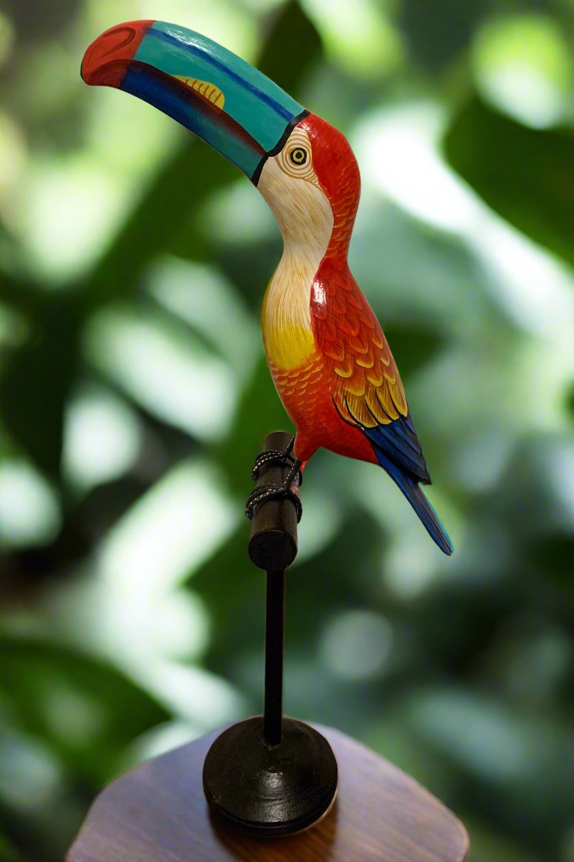 Colorful wooden toucan sculpture perched on a stand.