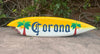 Corona surfboard sign with palm trees on both ends and a yellow-to-white gradient
