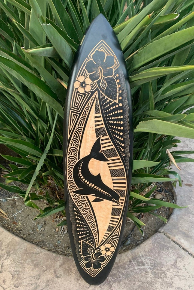 Decorative wooden surfboard with tribal floral etching in black and natural wood tones