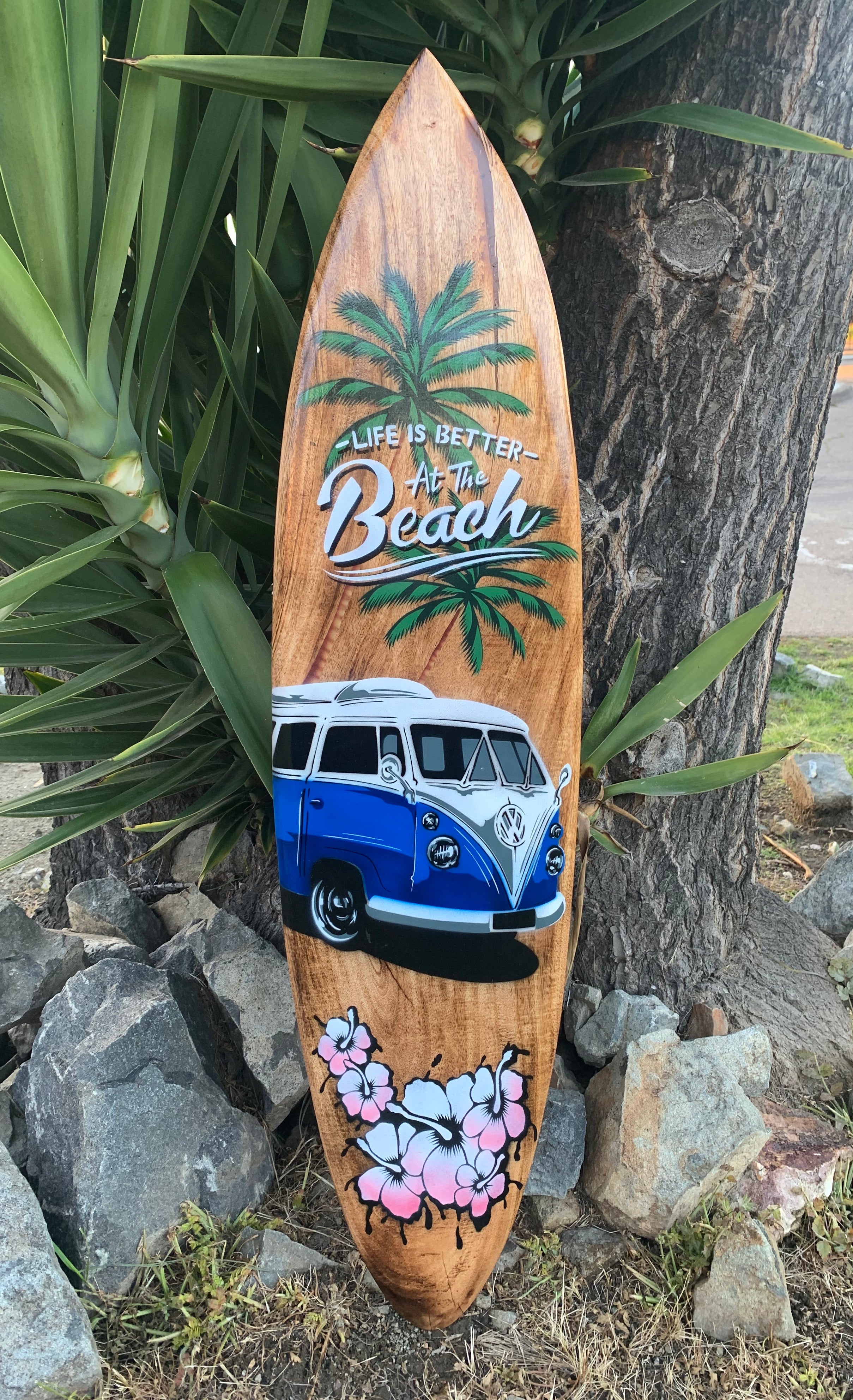 Wooden surfboard featuring palm trees, a blue VW van, and pink hibiscus flowers