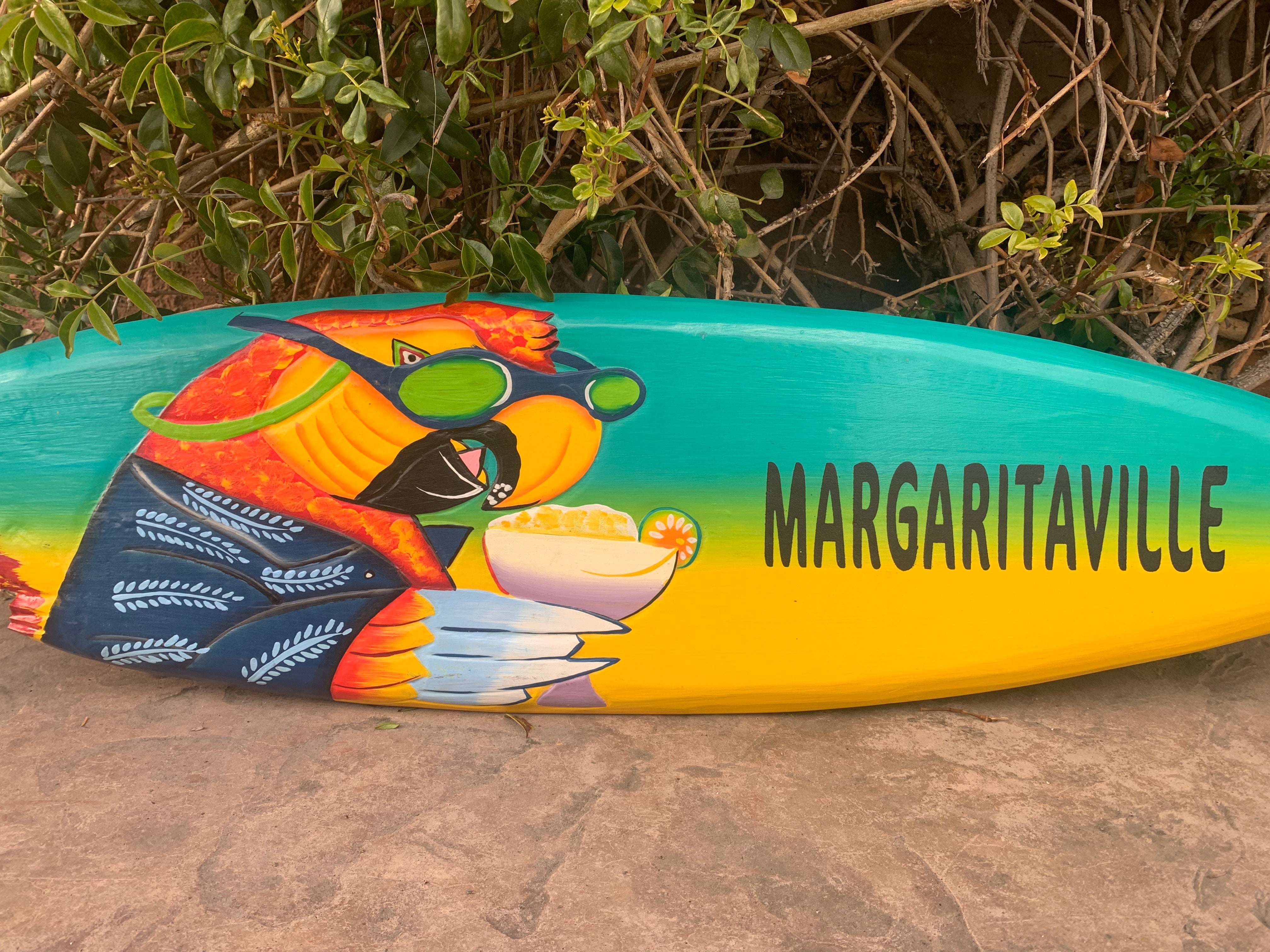 Colorful Margaritaville surfboard with tropical bird wearing sunglasses