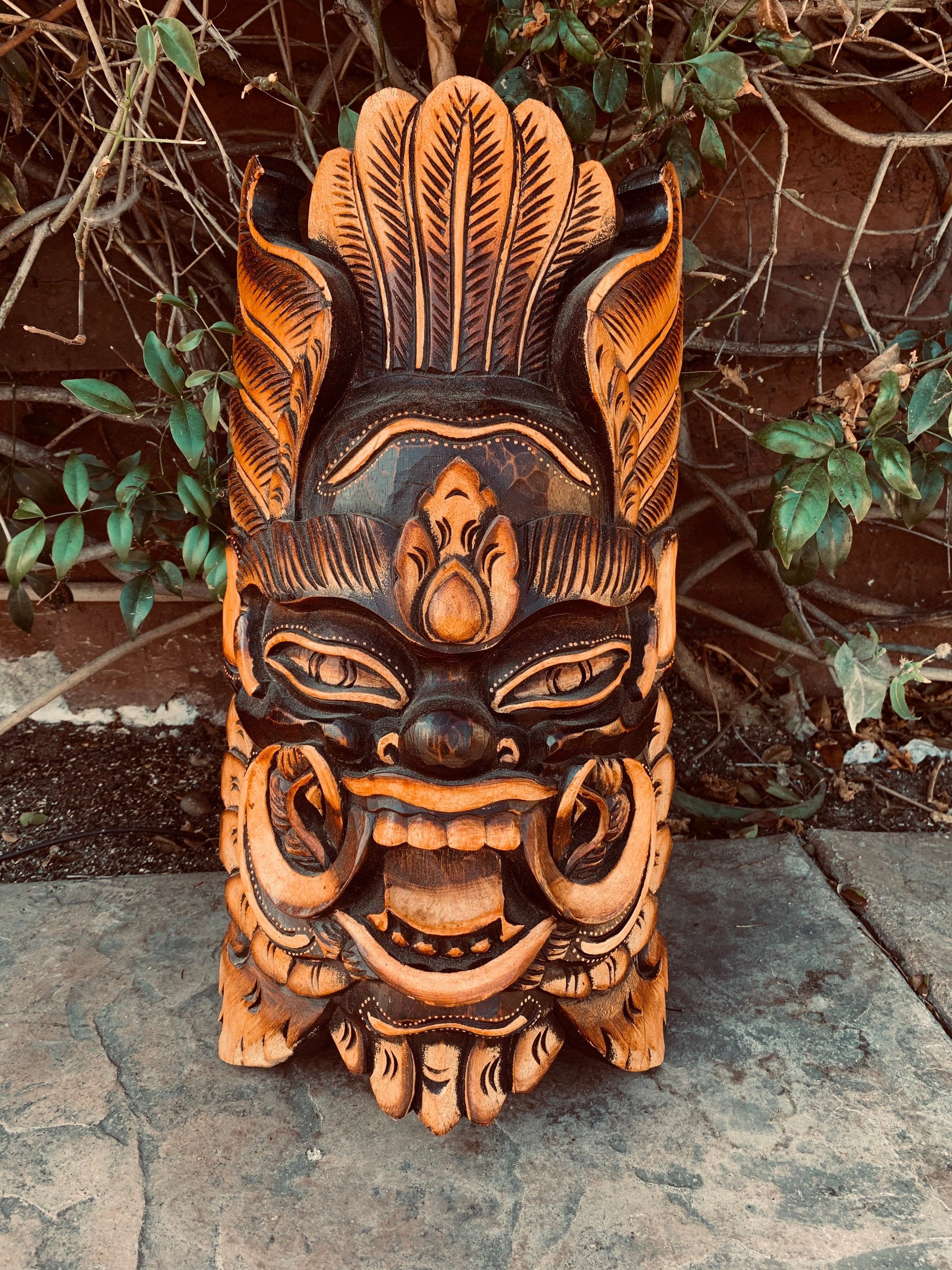 carved-wooden-tiki-mask-with-orange-and-black-detailing-and-a-fierce-expression