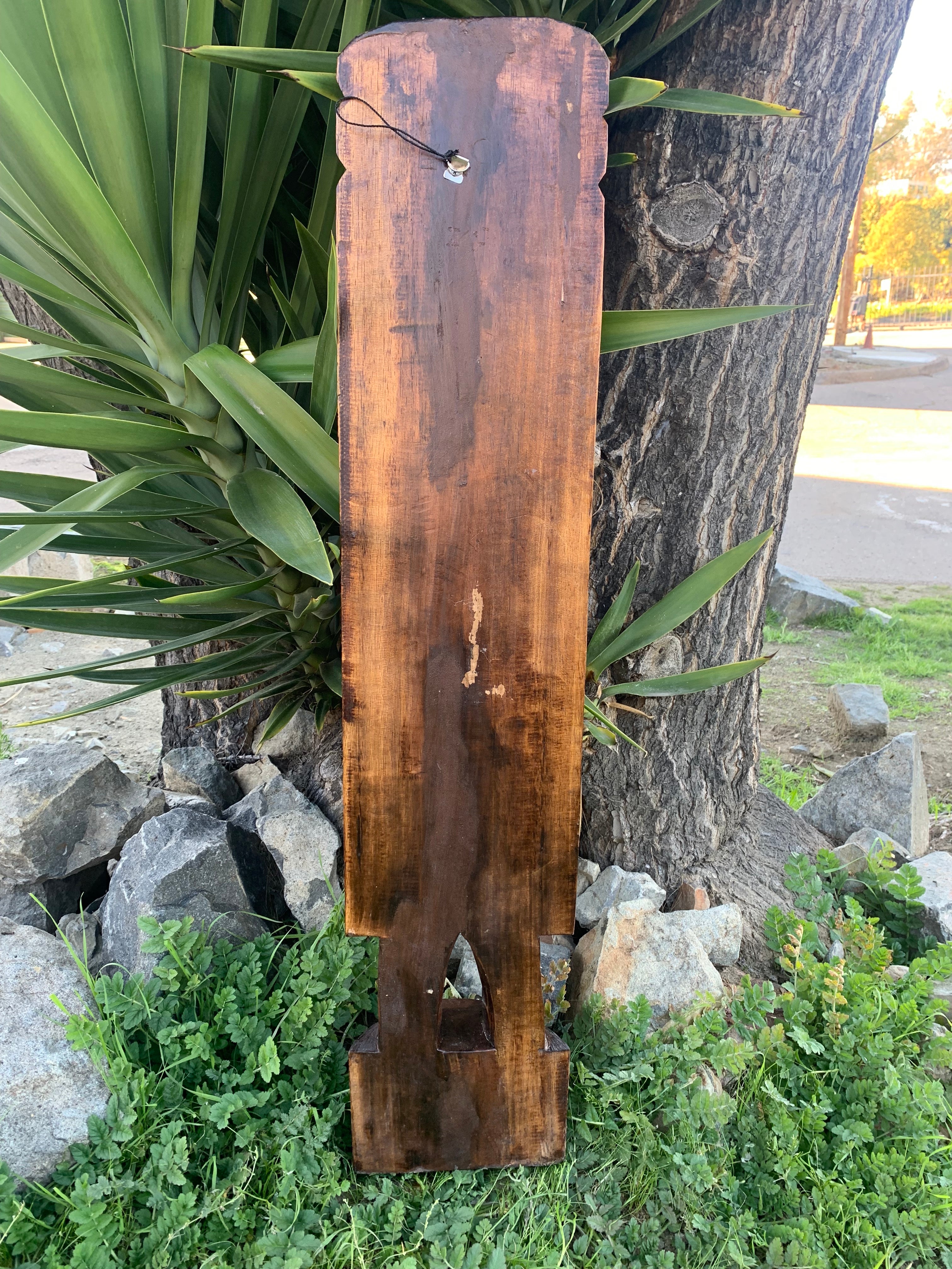 Rustic weathered wooden signboard leaning against a tree with arched-cut base