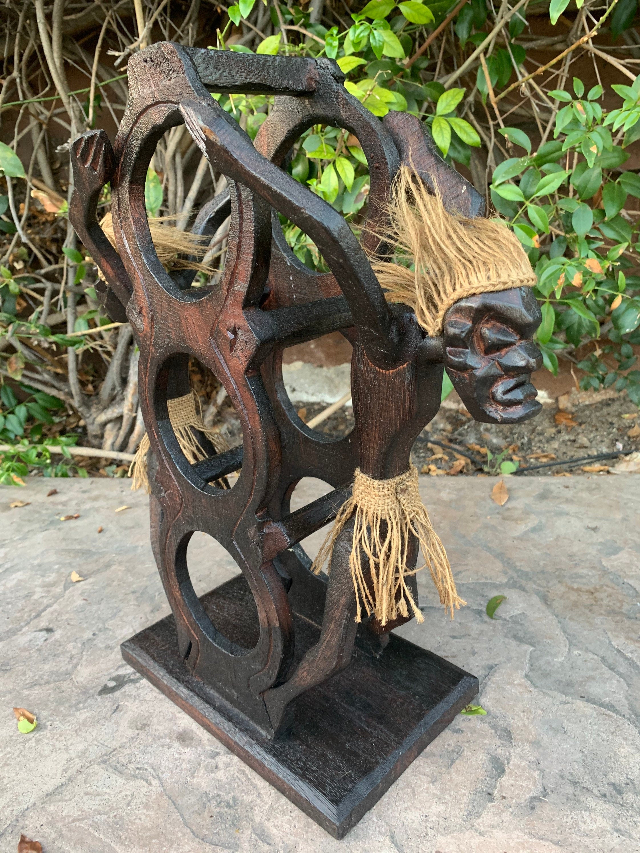 rustic wooden sculpture with a carved face and straw hair on a decorative circular wheel