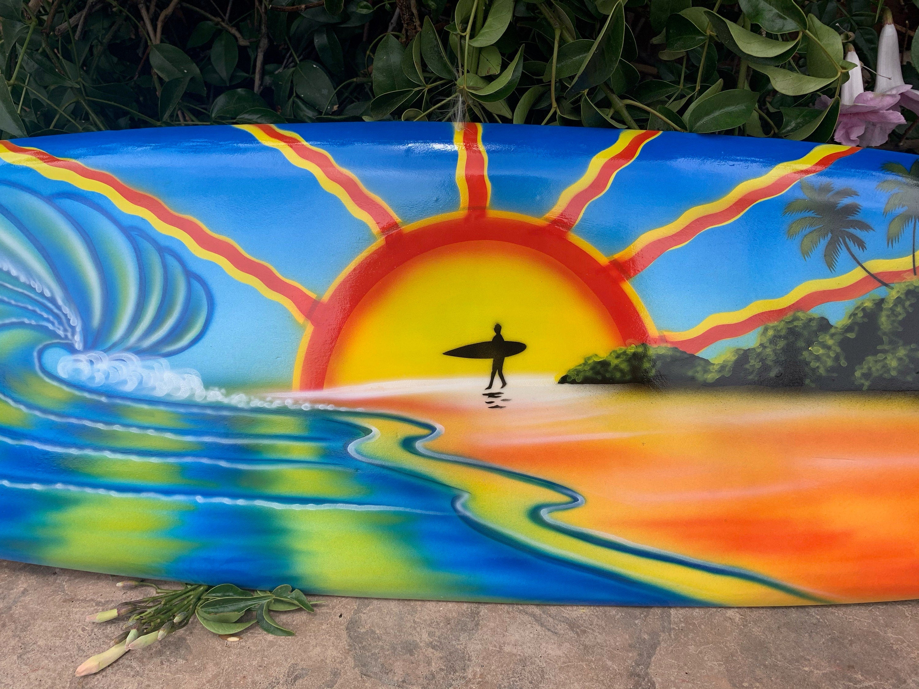 Silhouette of a surfer on a colorful sunset mural with waves, palm trees and beach
