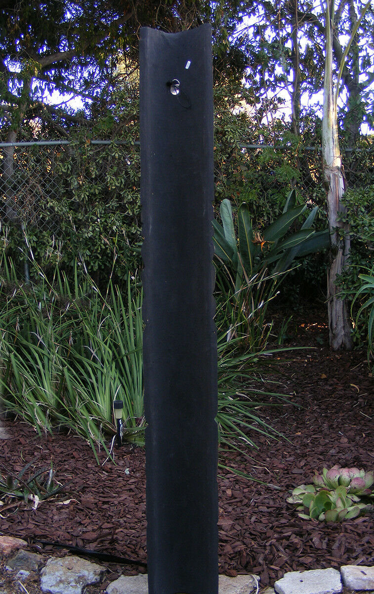 tall black garden pillar with a metal ring near the top in a landscaped yard