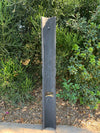 Tall dark slate post with a notch in a garden setting.