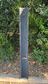 Tall slate garden post with a small metal hook in front of dense succulents.