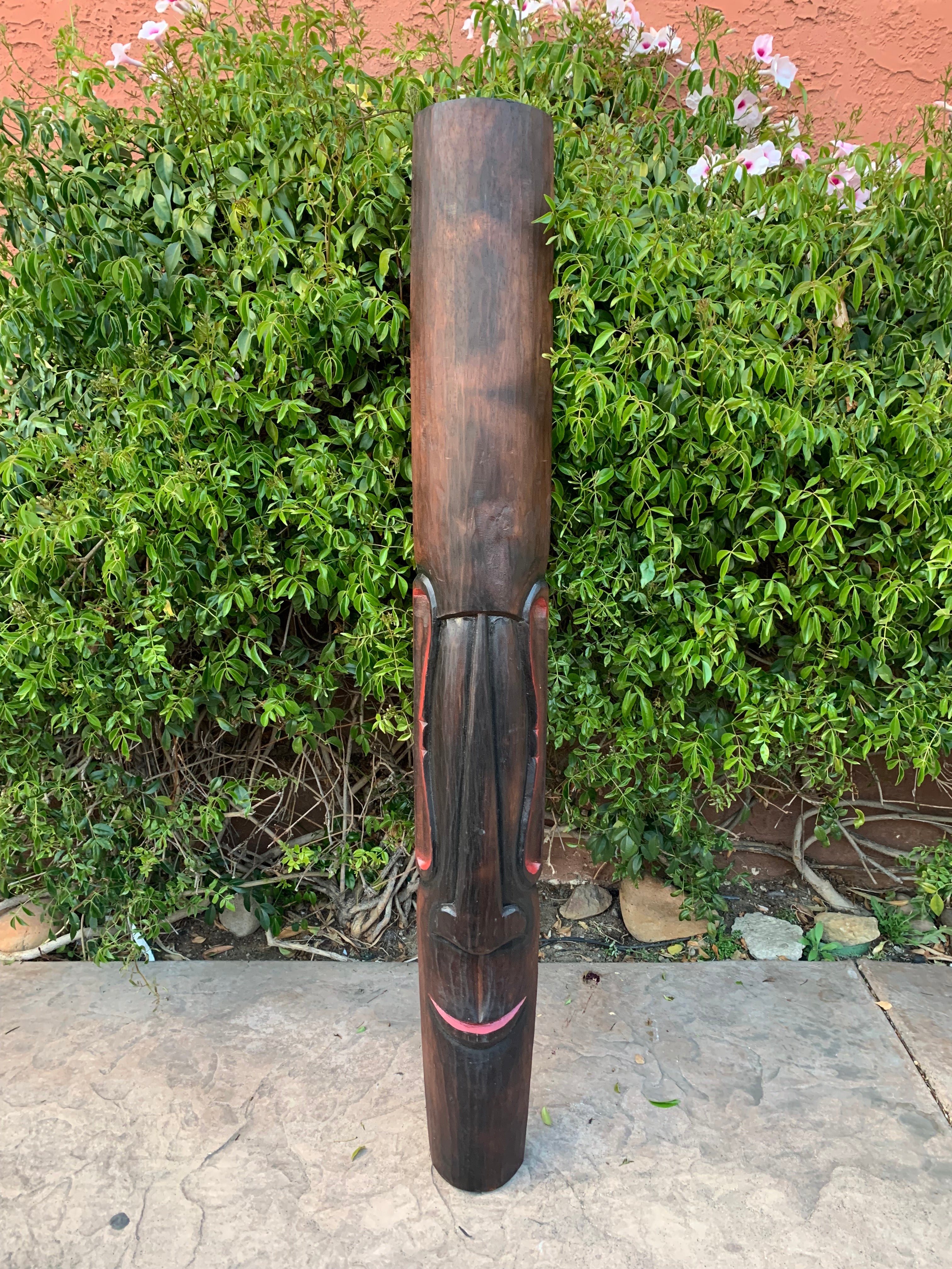 Tall wooden totem statue with a carved face outdoors
