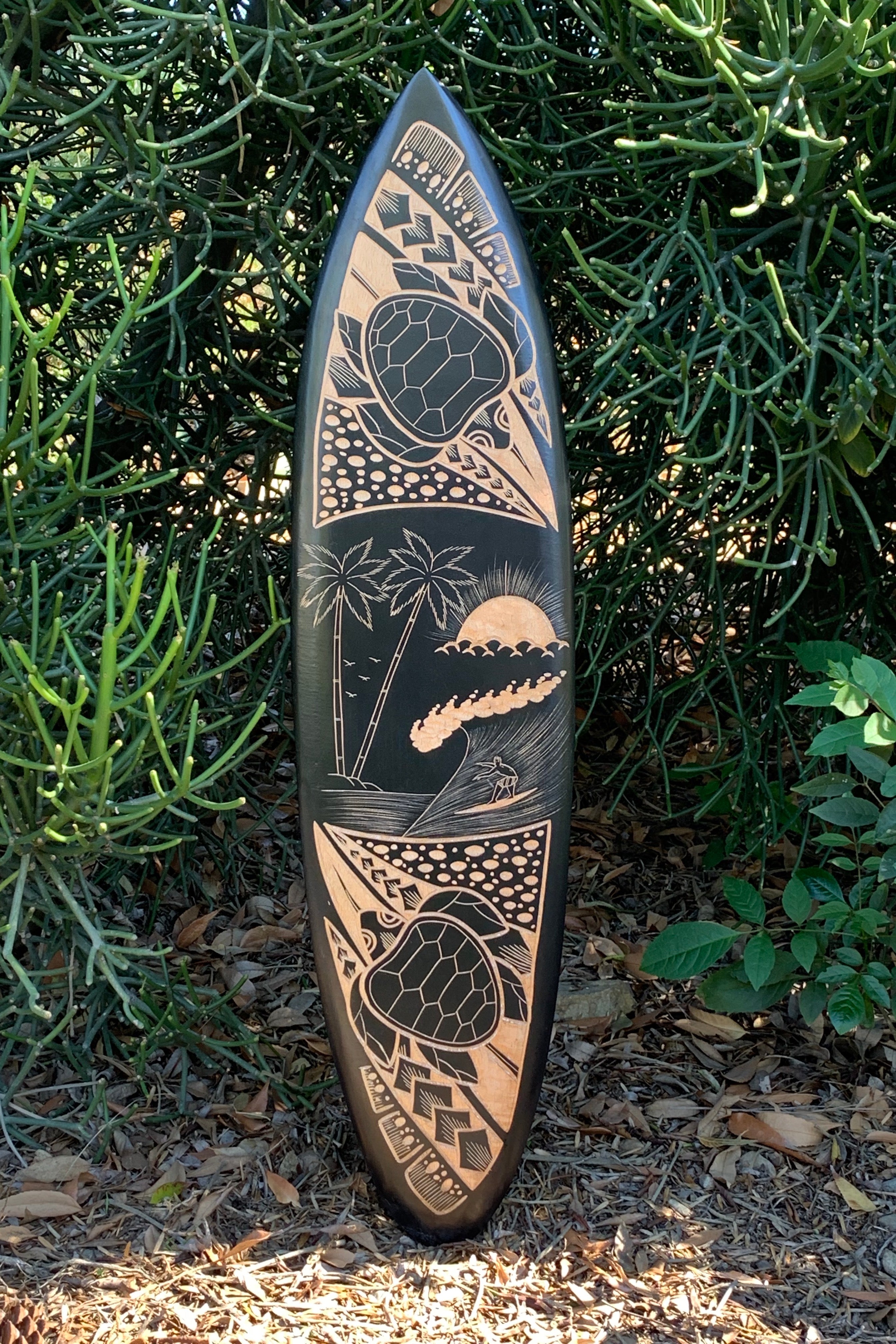 Polynesian-style tiki surfboard with palm trees, sun, waves, and a turtle-shell motif.