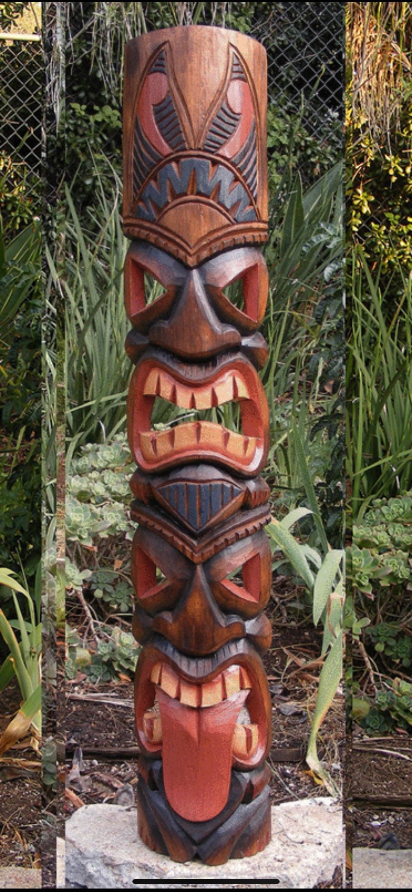 Tall carved wooden tiki totem with multiple faces and wide open mouth in a garden