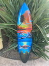 Colorful surfboard painting of a tropical sunset, palm trees, dolphins, and a sea turtle.