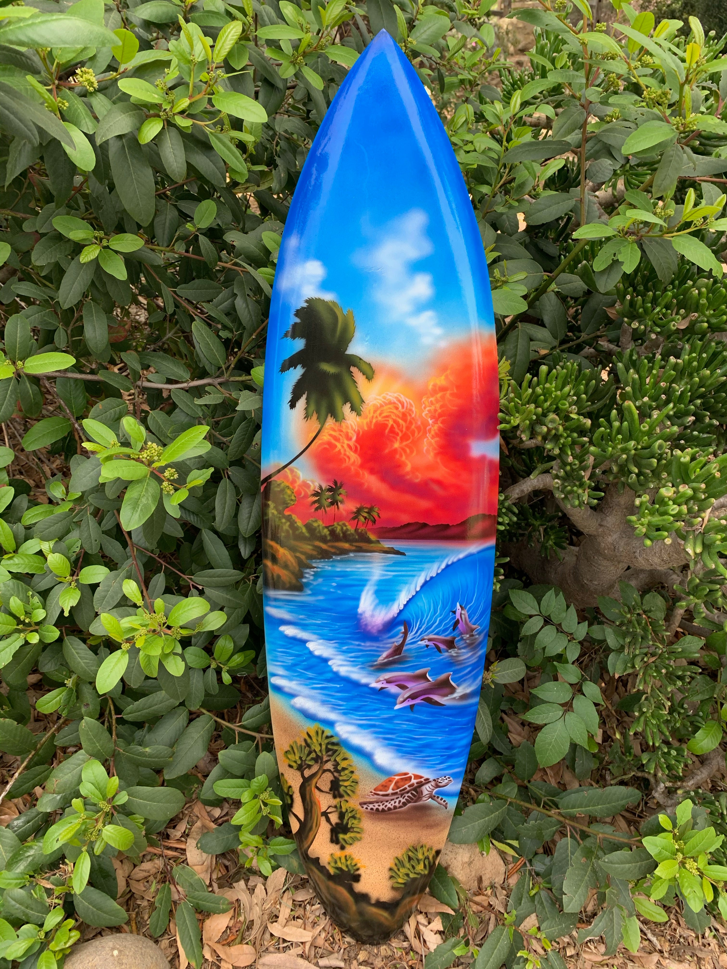 Colorful tropical surfboard design with palm trees, dolphins and a sea turtle on a sunny beach