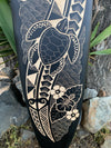 Carved turtle with floral and wave patterns on a dark panel
