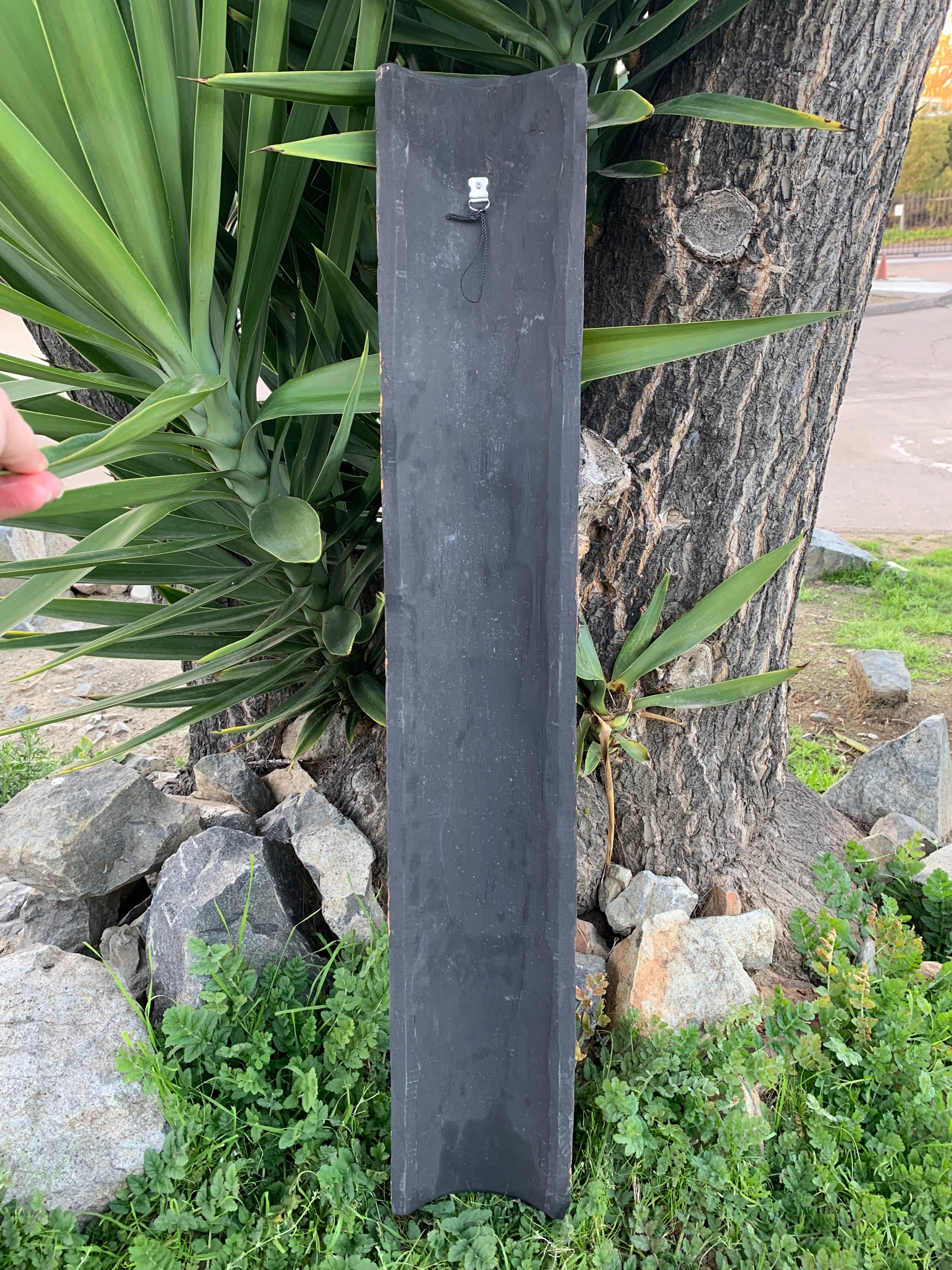 black slate signboard leaning against a tree in a landscaped garden