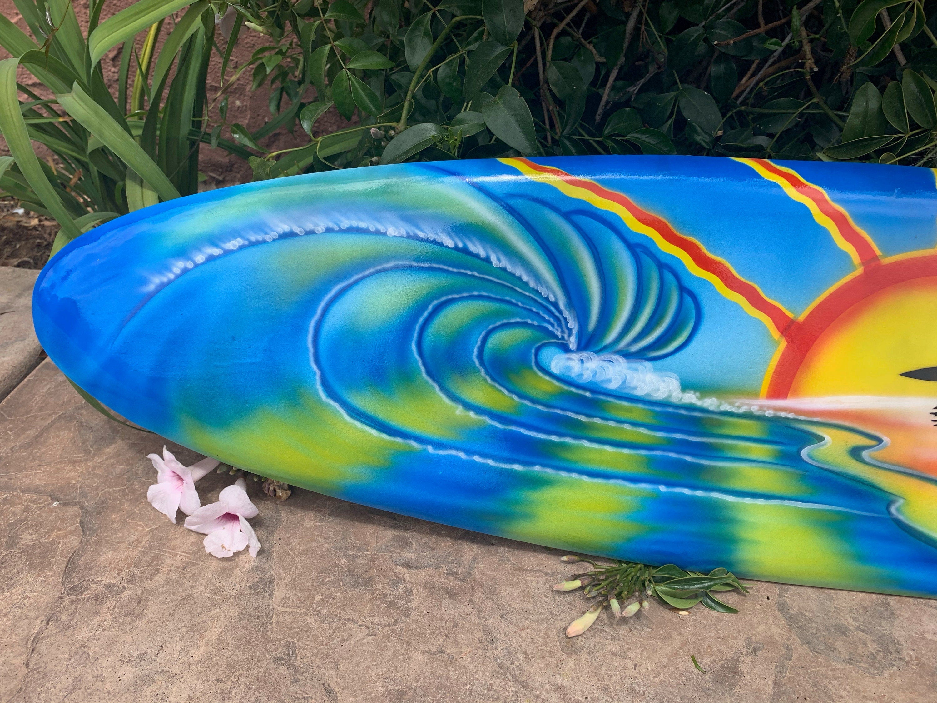 colorful surfboard with a curling ocean wave and sun design