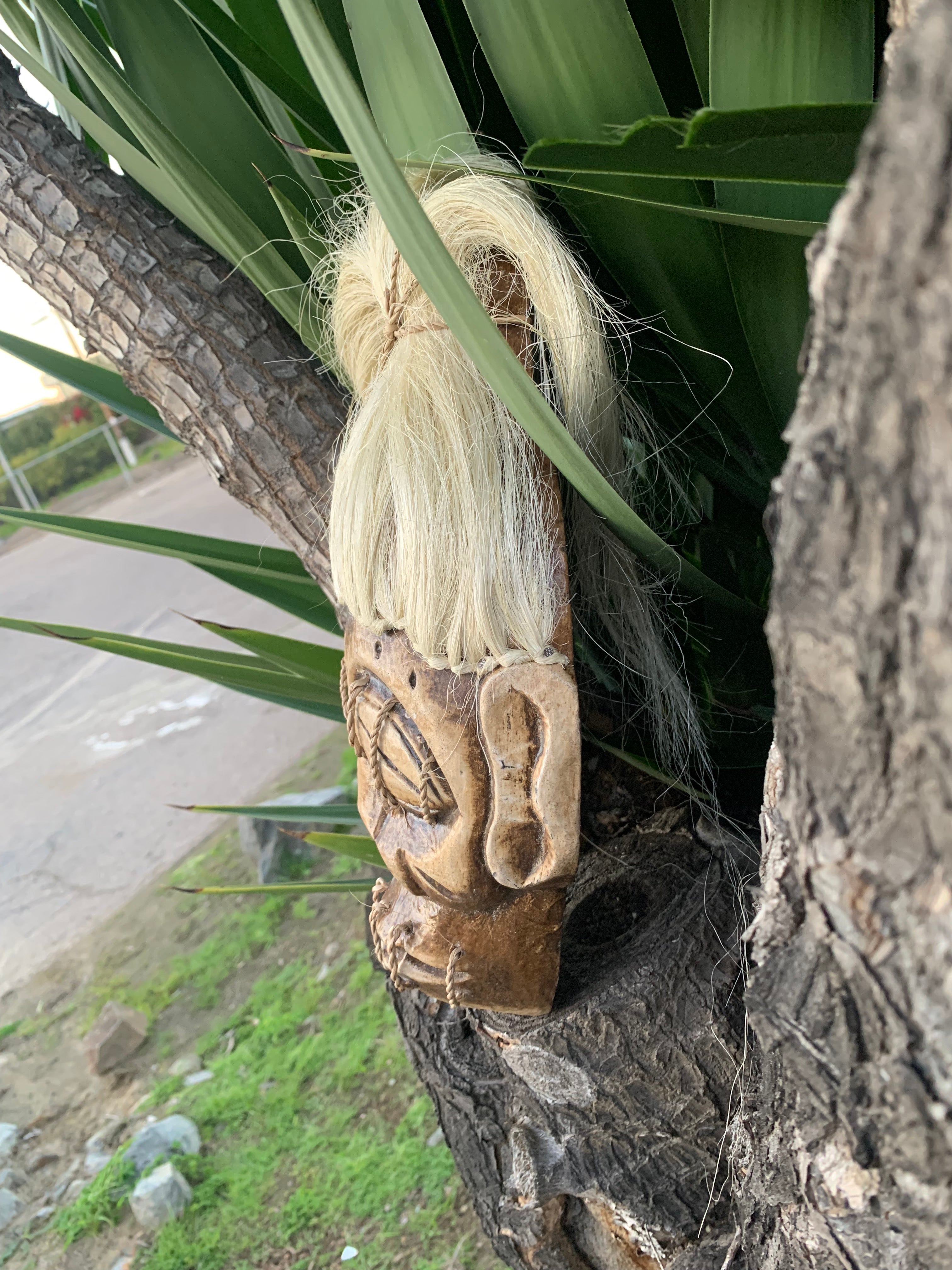 Carved wooden figure with a long blonde wig attached to a tree trunk