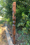 wooden carved totem pole beside green shrubs in a garden