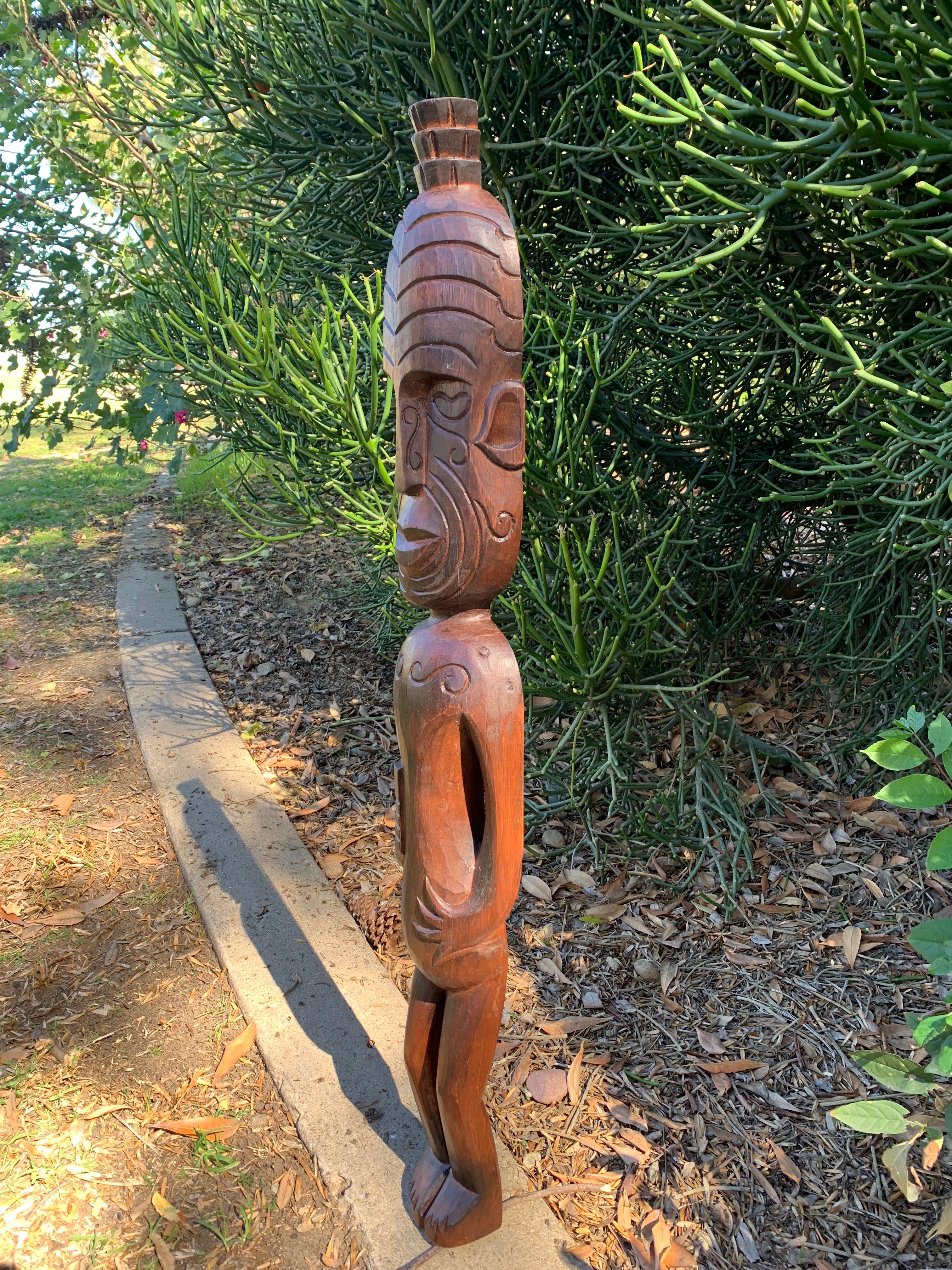 Wooden carved totem statue outdoors with a green succulent plant in the background