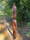 Wooden carved totem statue outdoors with a green succulent plant in the background