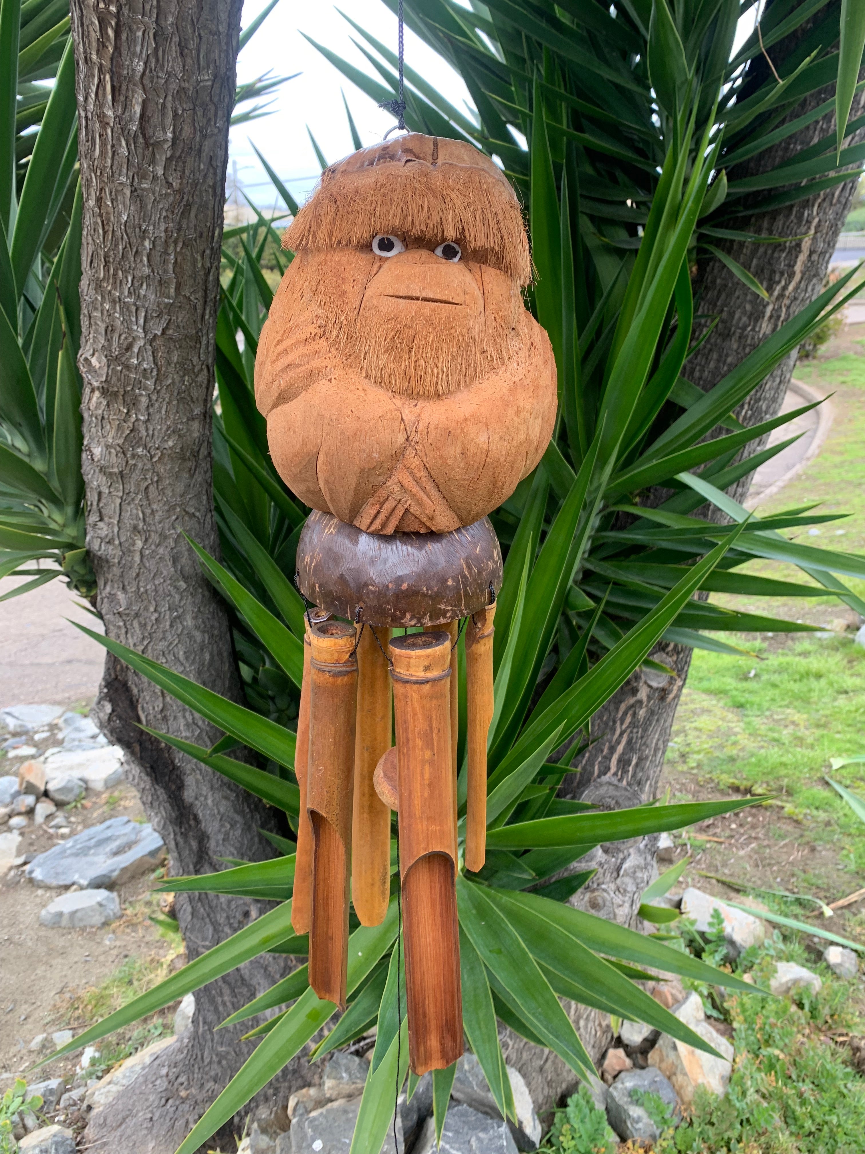 Wooden gnome wind chime with bamboo tubes hanging outdoors
