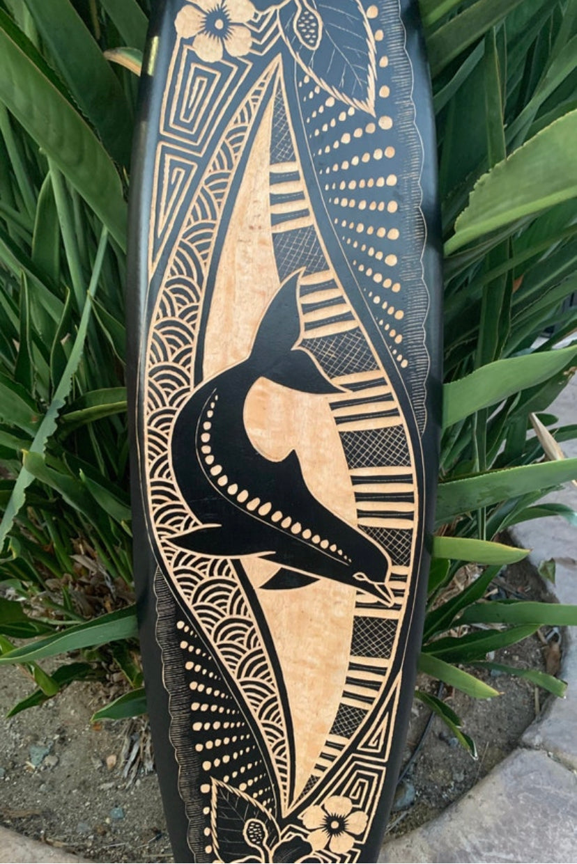Decorative wooden surfboard with a black tribal bird and geometric patterns.