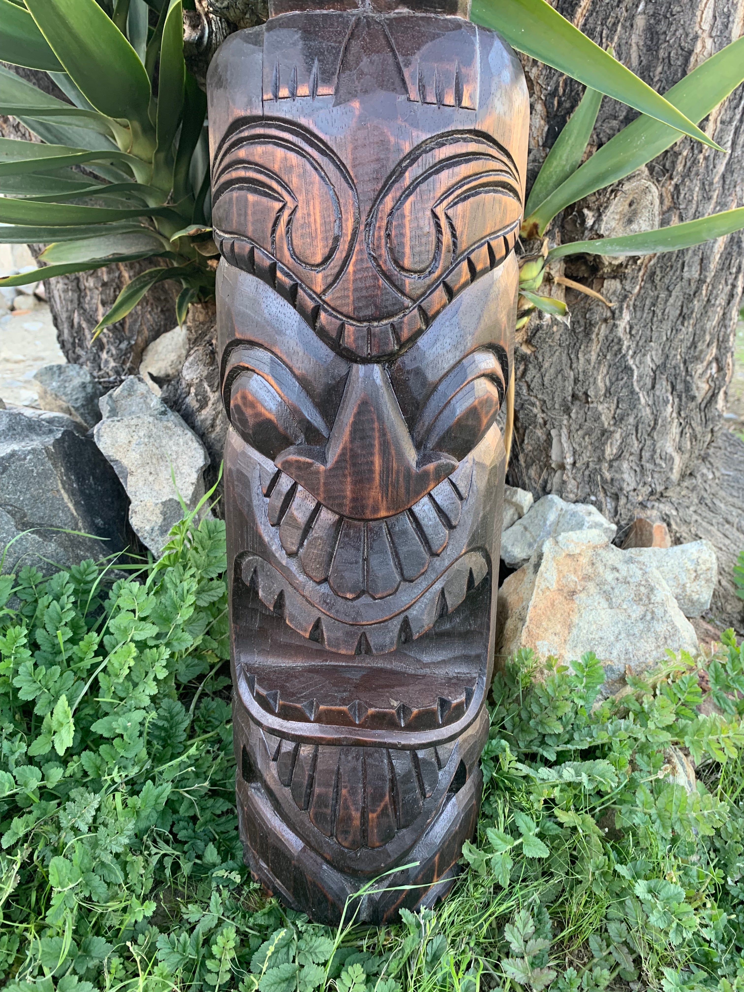 carved wooden tiki statue with exaggerated facial features in garden setting