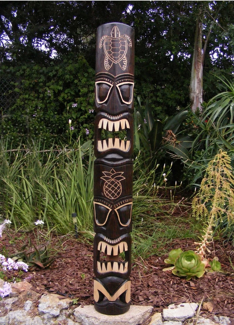 Wooden tiki totem pole carved with faces in a garden setting